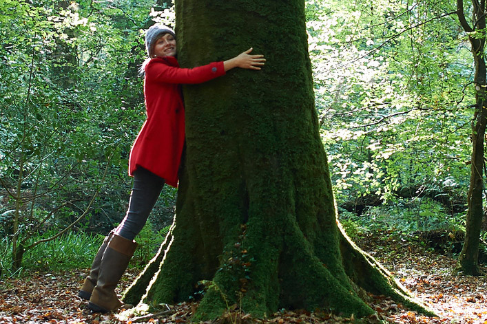 Person neben einem großen Baum in einem deutschen Wald